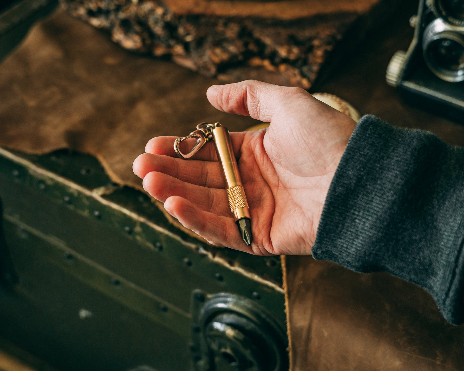 Overhead view of hand cradling brass screwdriver keychain with bit.