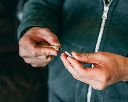 Pair of hands holding the brass screwdriver keychain putting a bit into the end.